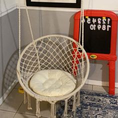 a white hanging chair in front of a chalkboard