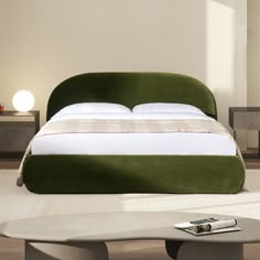 a green bed sitting in the middle of a room next to a table and chair