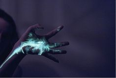 a person's hand with green and blue light painted on it