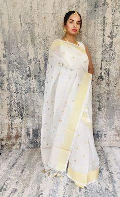 Simple white Kota Check inspired Banarasi saree with good zari dots embroidered all over the body. Zari palli simple and unique. Its just a very simple yet beautiful saree... Color White Saree is light , drapes easily , has a beautiful shine and overall a very good choice. The saree is ready to wear with falls, pico and beautiful handwoven tassels , and unstitched blouse fabric is included. Note: Colors that show up on your screen may vary slightly from the actual product due to variations in settings. Also, the actual product may appear to be different hues depending on the ambience lighting. Note: There may be very slight inconsistencies such as in the weave/motifs work, there being characteristics are not considered defects. Saree does not come with the jewelry shown in pictures. White Pre-draped Saree With Zari Weaving For Festivals, Traditional White Pre-draped Saree With Self Design, White Handloom Pre-draped Saree For Diwali, White Handloom Pre-draped Saree, White Cotton Silk Traditional Wear For Festive Season, White Saree For Puja And Festive Occasions, White Cotton Silk Pre-draped Saree For Wedding, Festive White Saree For Puja, White Zari Work Saree For Puja