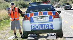 a police officer standing next to a car on the side of the road with an object in his hand