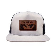 Colorado Elevation mountains faux leather patch in rawhide. Available in silver gray or black. Flat bill cotton twill front. Mesh back with adjustable snapback Urban Trucker Hat With Logo Patch For Outdoor, Logo Patch Snapback Hat For Outdoor Activities, Logo Patch Flat Bill Snapback For Outdoor Activities, Flat Bill Snapback Hat With Logo Patch For Outdoor, Outdoor Snapback Hat With Flat Brim And Logo Patch, Outdoor Trucker Hat With Flat Brim And Logo Patch, Flat Brim Trucker Hat With Logo Patch For Outdoor, Outdoor Flat Brim Snapback Hat With Logo Patch, Gray Snapback Hat With Logo Patch And Curved Brim