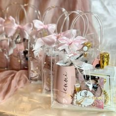 pink and gold wedding favors in clear plastic bags with bows on them, sitting next to each other