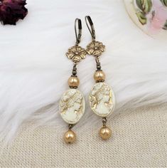 This listing features my handmade earrings created by me with unique elements!  The focal beads are ACRYLIC vintage style beads, done in cream with metallic gold accents that showcase a beautiful Victorian maiden on both sides.  These cameo beads are so nicely done!  I have added brass flower connectors and bright gold crystal cored faux pearls. The earrings are light due to the elements and measure 3 inches long including the brass lever back wires.  Thank you for visiting - please click here t Vintage Bronze Earrings With Round Beads, Vintage Bronze Round Bead Earrings, Handmade Vintage White Clip-on Earrings, Handmade Cream Jewelry For Jewelry Making, Nickel Free Cream Dangle Earrings, Cream Dangle Earrings Nickel Free, Handmade Cream Dangle Earrings, Handmade Cream Beaded Earrings Gift, Vintage Handmade Cream Jewelry