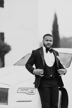 a man in a tuxedo standing next to a white car