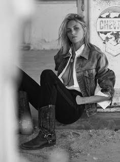 a woman sitting on the ground with her legs crossed and boots in front of her