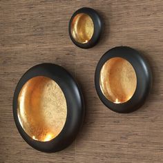 three black and gold plates sitting on top of a wooden table