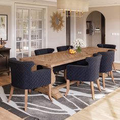 a large wooden table surrounded by blue chairs in a dining room with an area rug on the floor