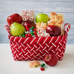 a red basket filled with lots of different types of fruit and candy on top of a table