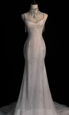 a white wedding dress on display in front of a black background