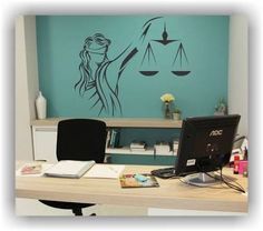 a desk with a computer on it and a lady justice decal above the monitor