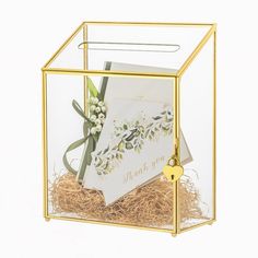 a card in a glass box with a key hanging from the handle and some flowers inside