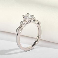 Imagine a slender band wrapping around your finger, with a graceful bow adorning its profile. This exquisite design adds a touch of whimsy and elegance to any ensemble. It's a symbol of grace and sophistication, perfect for those who appreciate understated beauty and charm.Carat Weight: 0.6 ctStone Size: 5.5 mmStone Type: Jeulia® StoneNumber of Stones: 1 Stone Color: Diamond WhiteStone Shape: RoundCarat Weight: 0.33 ctStone Size: 1.2,1.5 mmStone Type: Jeulia® StoneNumber of Stones: 14 Stone Colo Elegant White Gold Rings With Decorative Band, Elegant Adjustable Diamond Ring With Cubic Zirconia, Elegant Adjustable Cubic Zirconia Diamond Ring, Delicate Silver Diamond Ring For Formal Occasions, Elegant White Gold Diamond Ring With Decorative Band, Elegant Diamond Ring With Cubic Zirconia, Elegant White Ring With Decorative Band, Elegant Diamond Ring With Decorative Band Gift, Elegant Diamond White Ring With Decorative Band