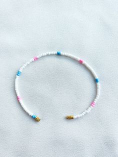 Handcrafted white beaded anklet/bracelet with pink and blue details. Made using small colourful round glass beads and finished with a gold-plated barrel clasp closure. Pair it with our matching Necklace.  * Weight: 3g   * Width: 5mm/2mm  * Made in UK  * Code: 111AWPBS The very best in unique, handmade pieces from BAM-BAM, our anklets and bracelets make great accessories for the beach, festival or club. These small beads have a dainty appearance and can take your best looks from day to night. White Beaded Strand Anklet, White Round Bead Anklets For Summer, White Round Beads Anklet For Summer, White Heishi Beads Friendship Bracelets For Vacation, White Beaded Anklets With Round Beads, White Round Beads Anklets For Vacation, White Heart Beads For Summer, White Beach Bracelet Beads, White Anklets With Colorful Beads As A Gift