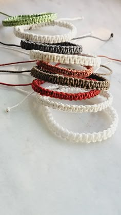 five different colored bracelets on a white counter top with strings attached to each one