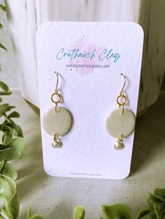 a pair of earrings sitting on top of a table next to some plants and leaves