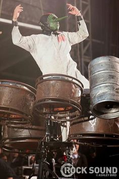 a man in white jacket playing drums on stage