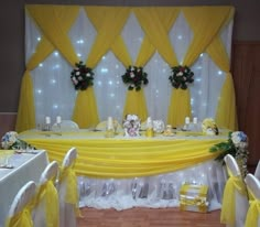 a banquet table with yellow drapes and white linens