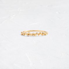 a gold ring with small leaves on the inside and outside, sitting on a white surface