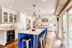 a kitchen with white cabinets and blue island