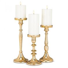 three brass candlesticks with white candle holders