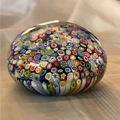 a close up of a glass object on a bed with a white sheet in the background