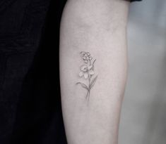 a small flower tattoo on the left arm