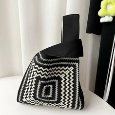 a black and white bag sitting on top of a table next to a vase with flowers