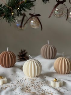 three candles sitting on top of a white sheet next to christmas ornaments and pine cones