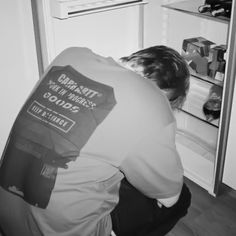 a man kneeling down in front of an open refrigerator with his head inside the door