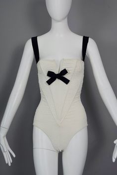 Features: - 100% Authentic CHRISTIAN LACROIX. - Ivory white wired corset bodysuit/ swimsuit with embossed brocade pattern. - Contrasting black strap and bow accent. - Tag reads: CHRISTIAN LACROIX PARIS Made in France, Size 38.  - Fabric Composition: 88% Nylon 12% Elastan - The black straps are a bit loose. - Excellent vintage condition. Will fit Small to Medium. Measurements taken laid flat, please double bust, waist and hips: Bust: 13.38 inches (34 cm) without stretching Waist: 10.63 inches (27 Chic White Underbust Corset, White Underwire Party Corset, White Underwire Corset For Parties, Cream Fitted Bodysuit With Lined Body, Fitted Cream Bodysuit With Lined Body, Fitted White Underwire Corset, White Fitted Underwire Corset, White Underwire Fitted Corset, Summer White Underwire Corset