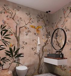 a bathroom with a tree mural on the wall next to a white toilet and sink