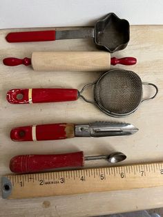 several different types of kitchen utensils on a wooden table next to a ruler