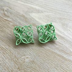 two pieces of green plastic sitting on top of a wooden table next to each other