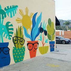 a painted wall on the side of a building with potted plants and sun glasses