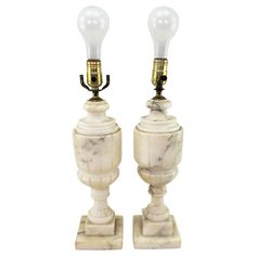 two white marble lamps with gold accents on each side and one light turned on the other