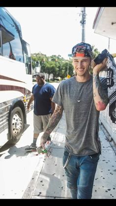 a man is walking down the sidewalk with his skateboard in front of him and two other men behind him