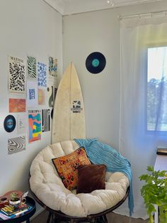 a surfboard sitting on top of a chair in a living room next to a window