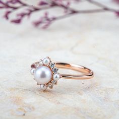 Product Description: Introducing Elara, a beautifully handcrafted ring that exudes elegance and timeless charm. At its center lies a 5mm Akoya pearl, radiating a soft, natural luster. Surrounding the pearl are smaller pearls and sparkling moissanite stones, delicately arranged to create a flower-inspired design. For those looking for an extra touch of luxury, the moissanite stones can be replaced with diamonds upon request. The Elara ring’s sweet, fresh aesthetic perfectly blends modern fashion with classic sophistication, making it ideal for daily wear, a memorable anniversary gift, or a meaningful promise ring. Design Concept: The Elara ring was crafted with nature’s beauty and elegance in mind, drawing inspiration from the delicate bloom of flowers. The soft glow of the Akoya pearl, pai Pearl Rings With Brilliant Cut For Anniversary, Timeless Pearl Ring With Brilliant Cut For Wedding, Elegant Pearl Ring With Halo For Wedding, Timeless Pearl Wedding Ring With Brilliant Cut, Timeless Brilliant Cut Pearl Wedding Ring, Timeless Wedding Pearl Ring With Brilliant Cut, Elegant Pearl Promise Ring With Halo Setting, Diamond Pearl Ring With Halo For Wedding, Elegant Pearl Ring With Halo Design For Wedding