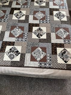 a bed with a brown and white quilt on it