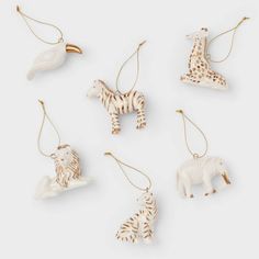 four different animal ornaments hanging from strings on a white surface, each with a giraffe, zebra, and elephant