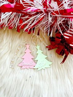 two christmas trees are sitting next to some red and white streamers on a fur surface