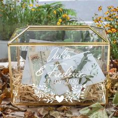 a glass box filled with envelopes sitting on top of leaves