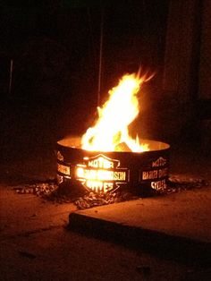 a fire pit sitting on top of a sidewalk next to a street sign with words written on it