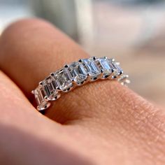 a woman's hand holding an engagement ring with three baguettes on it