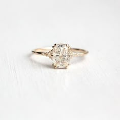 an oval diamond ring with three smaller diamonds on the band, set in yellow gold