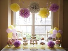 a table topped with lots of balloons and cake next to a window filled with flowers