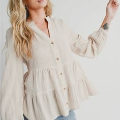 The Tiered Rustic Blouse With A Button-Down Front And Long Sleeves Exudes A Charming And Laid-Back Appeal. The Tiered Design Adds A Touch Of Bohemian Flair, Creating A Flowy And Relaxed Silhouette. The Rustic Aesthetic Lends A Vintage And Earthy Vibe To The Blouse, Making It A Versatile Piece For Both Casual And Semi-Formal Occasions. The Button-Down Feature Allows For Adjustable Styling Options, Whether You Choose To Wear It Open For A More Casual Look Or Buttoned Up For A Polished Appearance. Beige Relaxed Fit Top With Buttons, Casual Beige Blouse With Buttons, Oatmeal Tops For Spring Everyday Wear, Oatmeal Tops For Everyday Spring Wear, Feminine Neutral Long Sleeve Tops, Effortless Beige Blouse For Daywear, Beige Tops With Buttons For Spring, Beige Buttoned Tops For Spring, Spring Beige Button-up Blouse