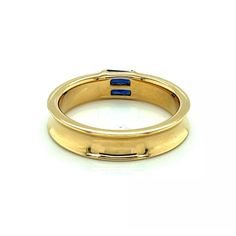 An elegant and authentic stack ring from Tiffany & Co. It is crafted from 18k yellow gold with a polished finish and features a 4.5mm wide concave design around the entire band with two channel set baguette sapphires.  It is signed by the designer with the gold content.    Brand:   Tiffany & Co.  Hallmark:  1997 Tiffany & Co. 750  Sapphire: 0.30ct  Material:  18k yellow gold  Measurement:  0.19" wide x 0.11" high  Ring Size:  6  Weight: 5.8 grams Luxury Yellow Gold Signet Ring With Baguette Cut, Luxury Yellow Gold Baguette Cut Signet Ring, Luxury 14k Gold Sapphire Ring Hallmarked, Luxury 14k Gold Sapphire Ring With Hallmark, Luxury Yellow Gold Ring With Polished Edges, Classic Stackable Sapphire Ring, Luxury Gold Emerald Ring With Round Band, Luxury Yellow Gold Rings With Polished Edges, Luxury Yellow Gold Emerald Ring With Polished Finish