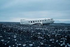 an airplane that is sitting on the ground in the middle of some black rocks and gravel